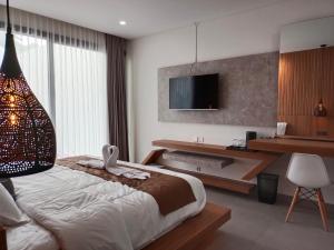 a bedroom with a bed and a desk and a television at Agarra Villa in Yogyakarta