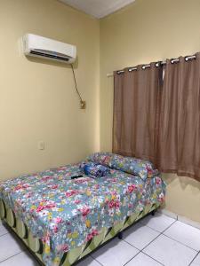 a bedroom with a bed with a floral comforter and a fan at Guest House da Amazônia in Manaus