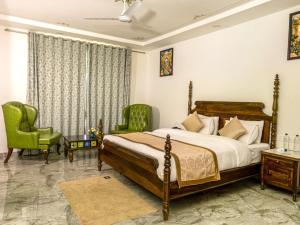 a bedroom with a bed and two green chairs at Jaisamand Garh Resort in Udaipur