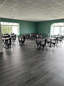 an empty room with tables and chairs and windows at Contact Hotel Utah Beach Carentan in Carentan