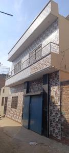 a brick building with a blue door and a balcony at UK Guest House in Chāh Mahūnwāla