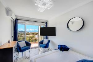 a bedroom with a bed and two chairs and a mirror at Panorama Majestic in Saint-Raphaël