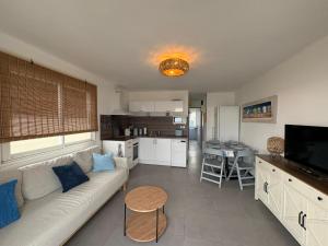 a living room with a white couch and a kitchen at Strandhuisje aan de Middellandse Zee in Palavas-les-Flots