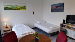 a room with two beds and a table and a tv at Chambre quadruple in Lully