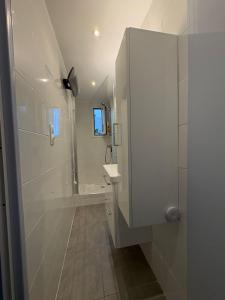 a white bathroom with a shower and a sink at Strandhuisje aan de Middellandse Zee in Palavas-les-Flots +12 photos