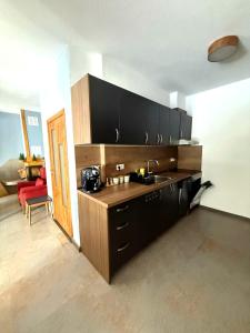 a kitchen with black cabinets and a red chair at Вила Планински перли, Дом 11 in Stoykite