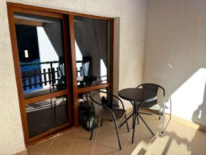 a room with a table and chairs and a balcony at Вила Планински перли, Дом 11 in Stoykite +1 photo