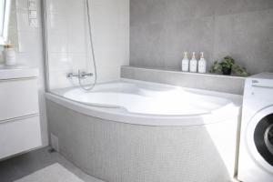 a bathroom with a tub and a washing machine at Iris Home in Székesfehérvár +3 photos