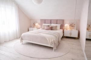 a white bedroom with a large bed and two night stands at Iris Home in Székesfehérvár