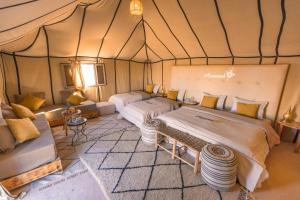 a bedroom with two beds in a tent at Azawad Desert Luxury Camp in Merzouga