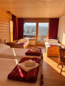 a bedroom with two beds and a large window at Hotel La Tour d'Aï in Leysin