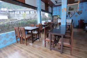 a restaurant with tables and chairs and a large window at Brahamkamal Resort in Gupta Kāshi