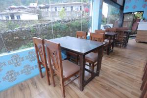 a table and chairs in a restaurant with a window at Brahamkamal Resort in Gupta Kāshi +20 photos