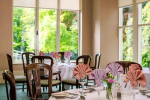a dining room with tables and chairs with pink napkins at Penmorvah Manor Hotel in Falmouth
