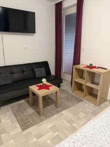 a living room with a black couch and a table at APARTMAN i SOBA HADELA in Sveti Martin na Muri