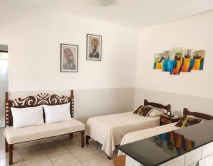 a room with two beds and a chair and paintings at Casa Inteira Com Total Privacidade e Quintal in Pará de Minas