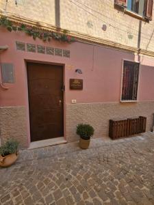 a pink building with a door and a potted plant at B&B A due passi dal centro in Castelfidardo