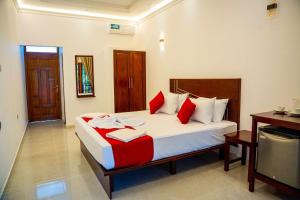 a bedroom with a large bed with red and white pillows at So-J Beach Villa in Trincomalee