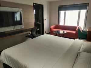 a hotel room with a bed and a couch and a tv at Crystal Residency - Panjappur Trichy in Pūngudi