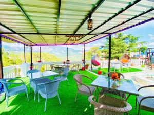 a patio with tables and chairs on the grass at Hotel Rana Taradevi in Shimla