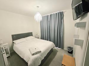 a small bedroom with a white bed and a television at 3 Guest Rooms in a 3bed house with kitchen, ENSUITE options also available in Telford