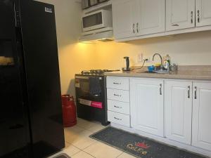 a kitchen with white cabinets and a black refrigerator at Cozy Modern flat in Tunapuna