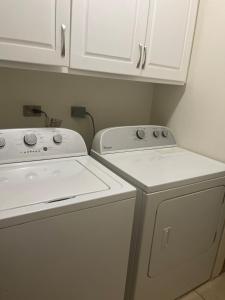 a kitchen with white cabinets and a washer and dryer at Cozy Modern flat in Tunapuna