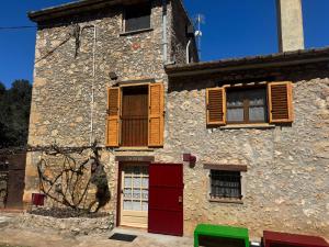 an old stone building with red doors and windows at Can Resiu in Serinyà