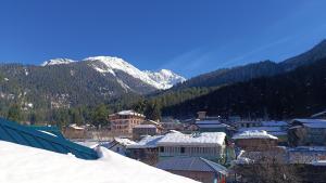 a town covered in snow with a mountain in the background at Himalayan bite pulga in Kalgha