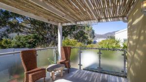 a porch with two chairs and a table on a balcony at Villa Oceanic Escape in Hout Bay