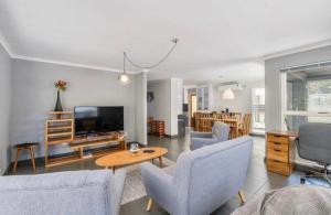 a living room with a couch and a tv and chairs at Villa Oceanic Escape in Hout Bay