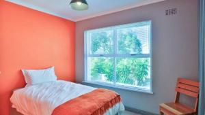 an orange bedroom with a bed and a window at Villa Oceanic Escape in Hout Bay +50 photos