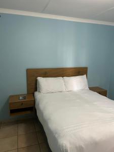 a bedroom with a white bed with a wooden headboard at Masakwe BNB in Soweto
