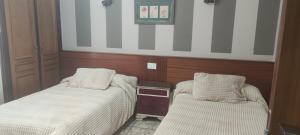 a bedroom with two beds and a table with a drawer at HOSTAL RESTAURANTE MILAN II in San Clemente