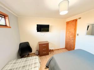 a bedroom with a bed and a chair and a television at Hospedaje Amore per il lago in Villarrica