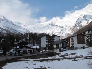 a village with snow covered mountains in the background at Kontiki in Saas-Fee