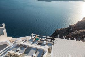 a woman sitting on a cruise ship looking out at the water at On The Rocks - Small Luxury Hotels of the World in Imerovigli