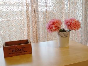 a vase with pink flowers on a table next to a box at Volos Seaside Studio in Volos