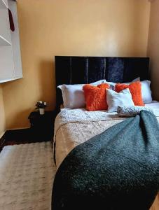 a bedroom with a bed with orange and white pillows at Baobab in Webuye