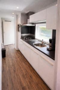 a kitchen with white cabinets and a wooden floor at 't Vrolijke Uusje in Scharendijke +4 photos