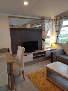 a living room with a tv and a couch and a table at Sunny sands retreat in Skipsea