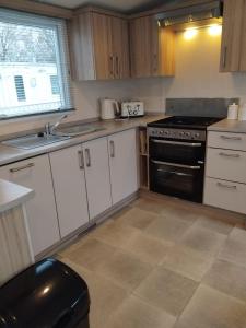 a kitchen with white cabinets and a black stove at Sunny sands retreat in Skipsea