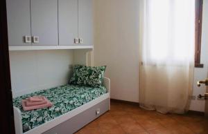 a small room with a bed with a green blanket and a pillow at AR House in Clusane sul Lago