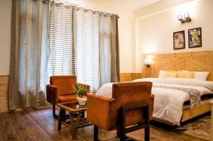 a bedroom with a bed and two chairs and a table at Devdar Heights in Jagatsukh