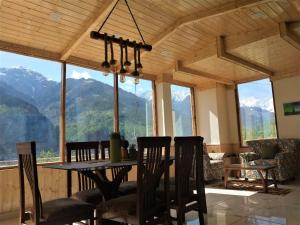 a dining room with a table and chairs and mountains at Devdar Heights in Jagatsukh