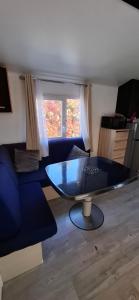 a living room with a table and a blue couch at Mobil home proche Fréjus - Camping 4 étoiles in Puget-sur-Argens