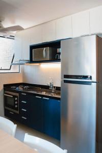 a kitchen with a stainless steel refrigerator and a microwave at Villas House - Praia Formosa - Cabedelo in Cabedelo