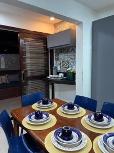 a wooden table with blue chairs and plates on it at Labonita House - Pilar in Itamaracá