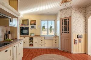 a large kitchen with white cabinets and a window at Slätterne Gård B&B in Sandviken +14 photos