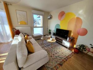 a living room with a couch and a flat screen tv at Appartement lumineux proche Genève et Jura 3 chambres, terrasses et parking in Gex